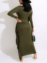 Back view of a woman in an olive green long-sleeved maxi dress with fringe detailing.