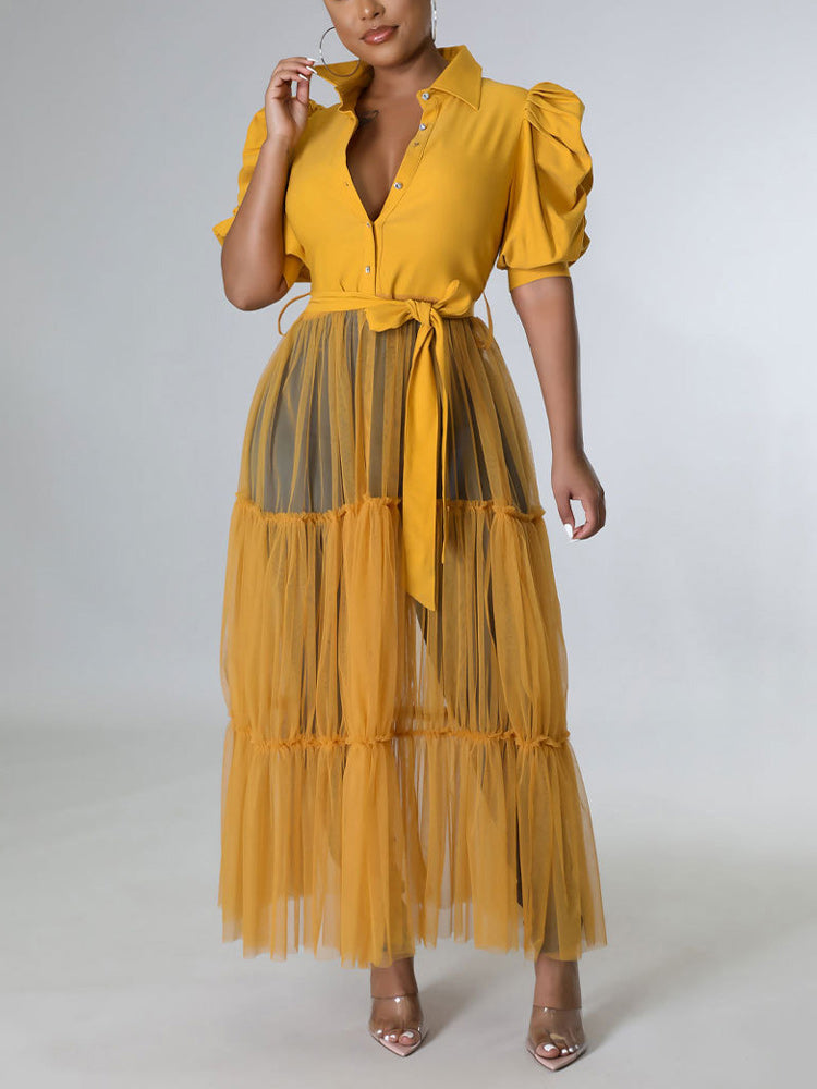 Woman wearing a mustard yellow maxi dress with puffed sleeves and a tiered tulle skirt