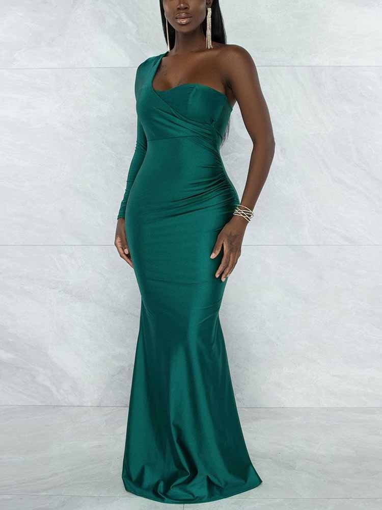 Side view of a woman in a green, one-shoulder formal gown with ruching details and a flowing mermaid skirt.
