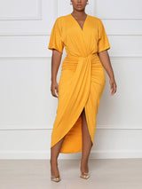 Woman wearing a yellow V-neck wrap dress with short sleeves, ruched waist, and asymmetrical hem with a slit.