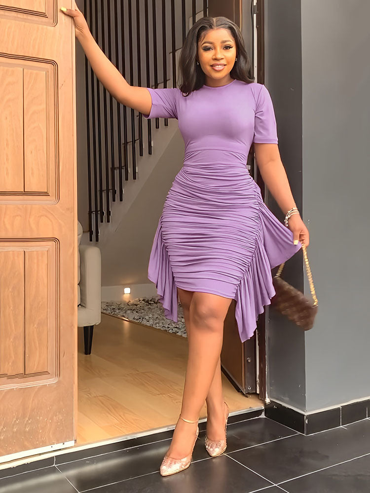 Woman in a purple ruched dress holding a furry handbag.