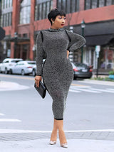 Woman wearing a black rhinestone midi dress and holding a black clutch.