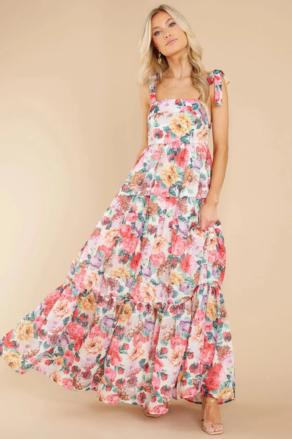 Close-up of the floral pattern and tiered design of a maxi dress worn by a woman.