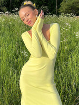 Close-up of a woman in a yellow ribbed knit maxi dress with long sleeves and a sweetheart neckline.