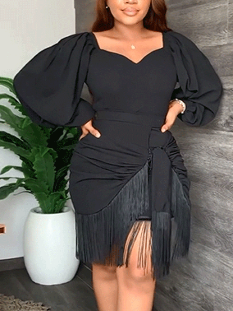 Front view of a woman in a black dress with puff sleeves and fringe detail.