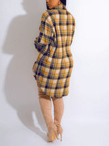 Woman wearing a yellow and navy plaid shirt dress with thigh-high beige boots, back view.