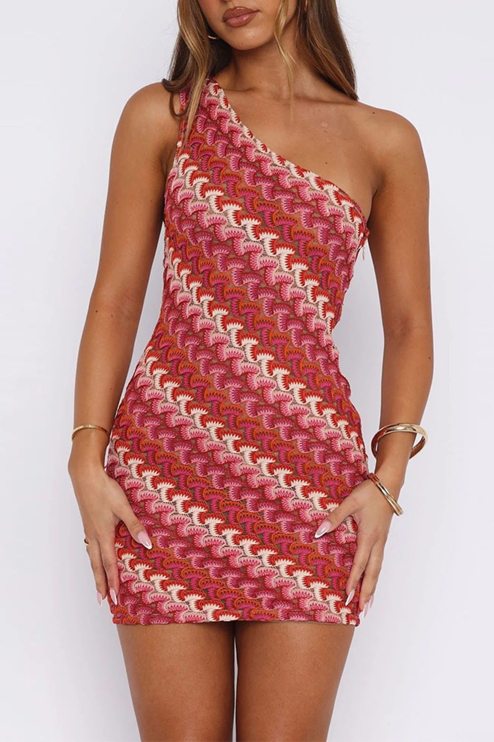 Model wearing a red and pink one-shoulder knit dress with a geometric pattern