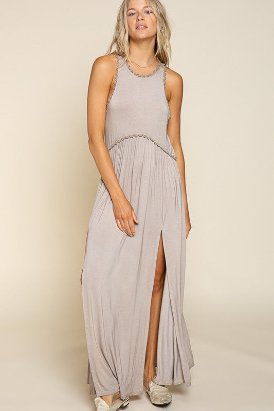 front view of a woman in a grey sleeveless maxi dress with a decorative trim and high side slits