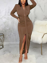 Woman wearing a brown long-sleeve ruched midi dress with a high slit.