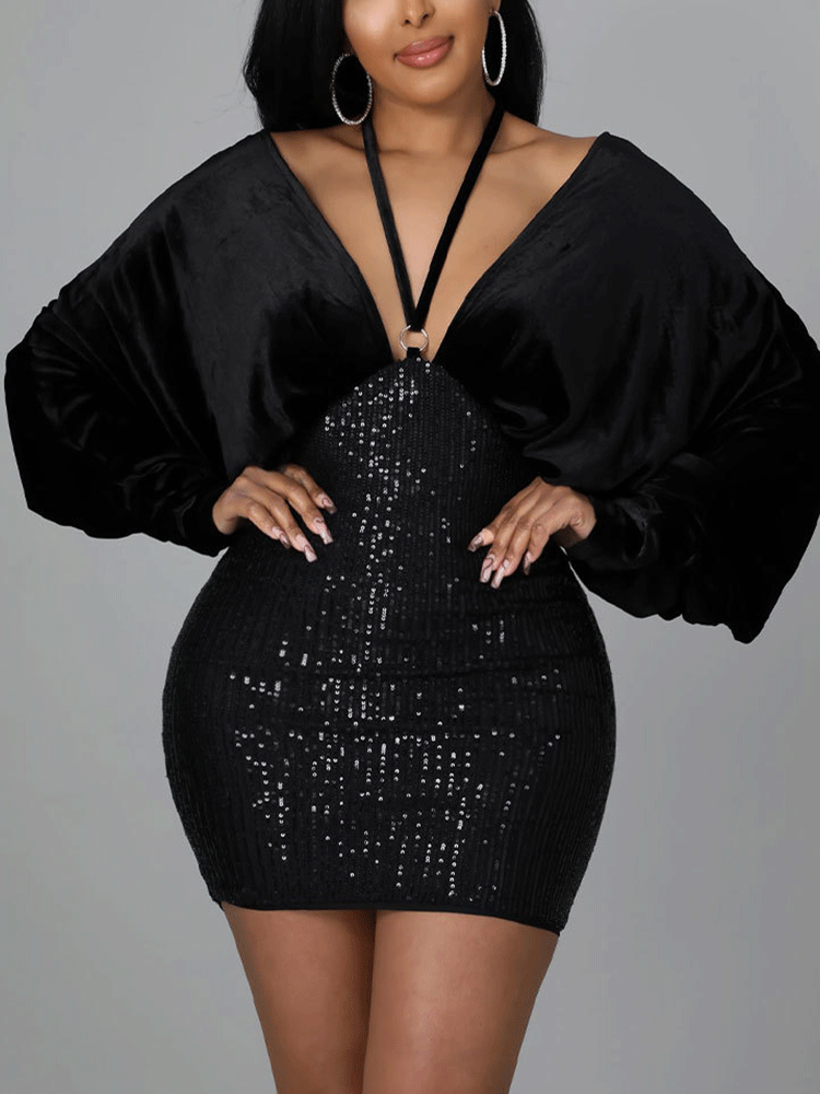 Woman wearing a black velvet and sequin mini dress with dolman sleeves