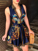 Woman wearing a sleeveless V-neck mini dress with a peacock print and tie waist.