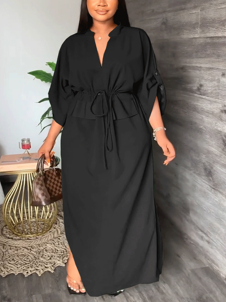 Woman wearing a long black dress with a v-neck, drawstring waist, and side slits.