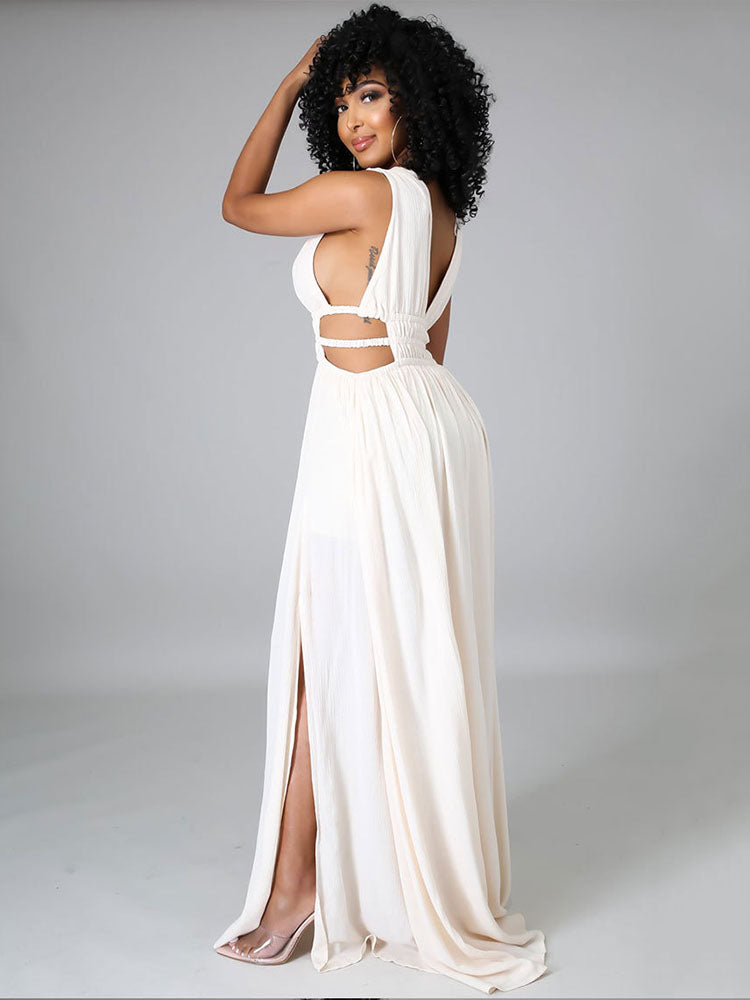 Side view of a woman in an off-white sleeveless maxi dress with a plunging V-neck, cut-out waist details, and a high slit, with her hand touching her hair.