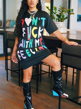 Woman in a black t-shirt dress with graphic print and knee-high boots.