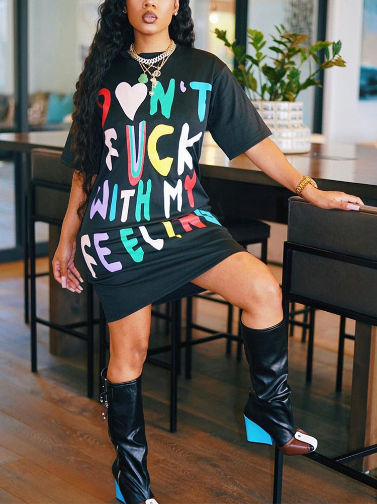 Woman in a black t-shirt dress with graphic print and knee-high boots.