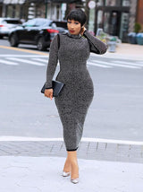 Front view of a woman in a black rhinestone midi dress, standing on a street.