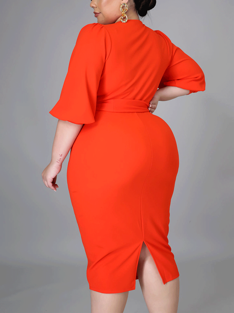 Back view of a woman in an orange pencil dress with a vent at the back.