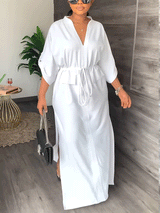 Woman wearing a white V-neck maxi dress with a drawstring waist and side slits.