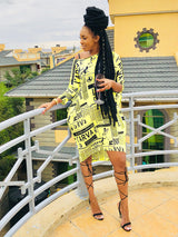 Woman in a yellow newspaper print t-shirt dress and black strappy heels, posing on a balcony.