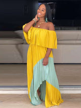 Woman smiling and posing in a yellow and mint green off-the-shoulder pleated maxi dress.
