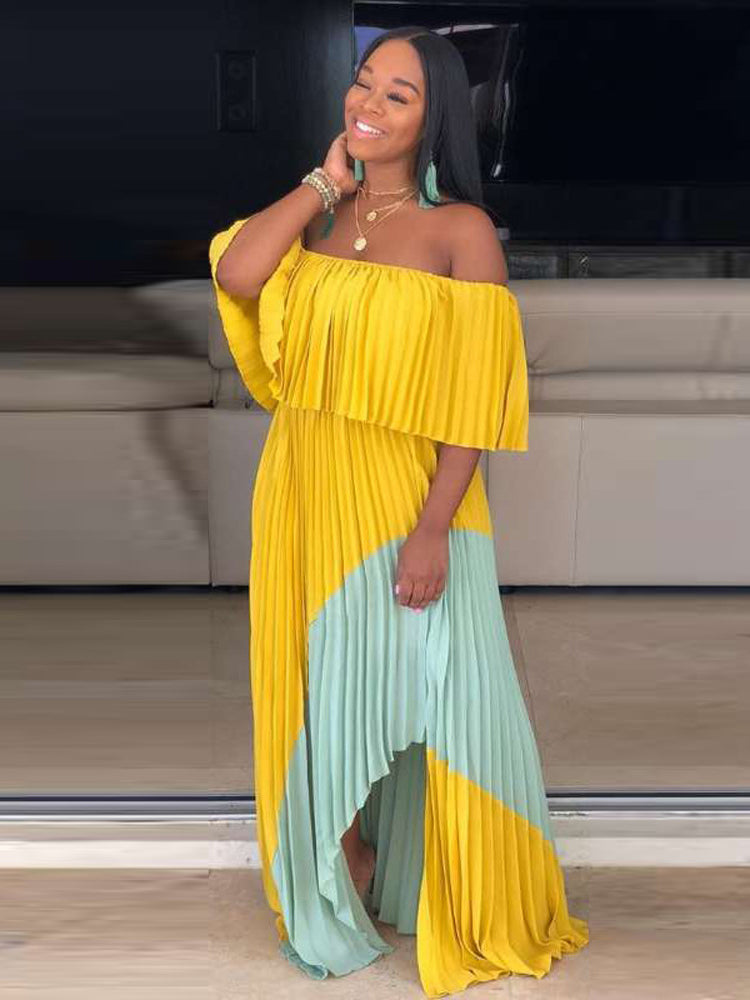 Woman smiling and posing in a yellow and mint green off-the-shoulder pleated maxi dress.