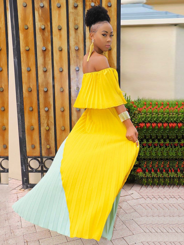 Woman posing in a yellow and mint green off-the-shoulder pleated maxi dress outdoors.