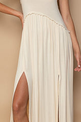 Close-up of the thigh-high slit on a cream-colored maxi dress