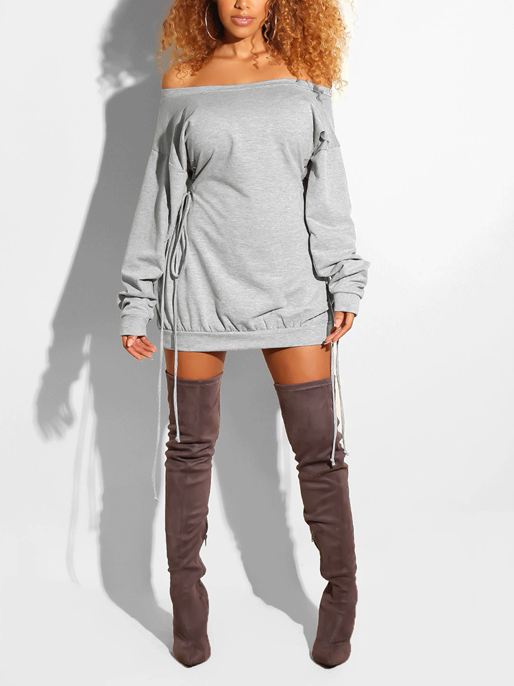 Woman wearing a light grey off-the-shoulder mini dress with drawstring details on the sides and long sleeves, paired with knee-high boots.