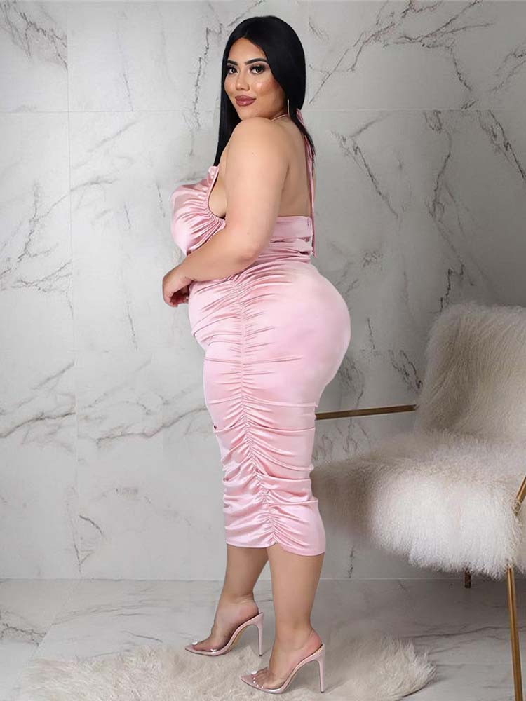 Side view of a woman wearing a pink satin ruched halter neck sheath dress.