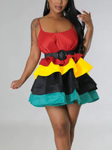 Woman in a red, yellow, black, and teal tiered mini dress with a black belt.