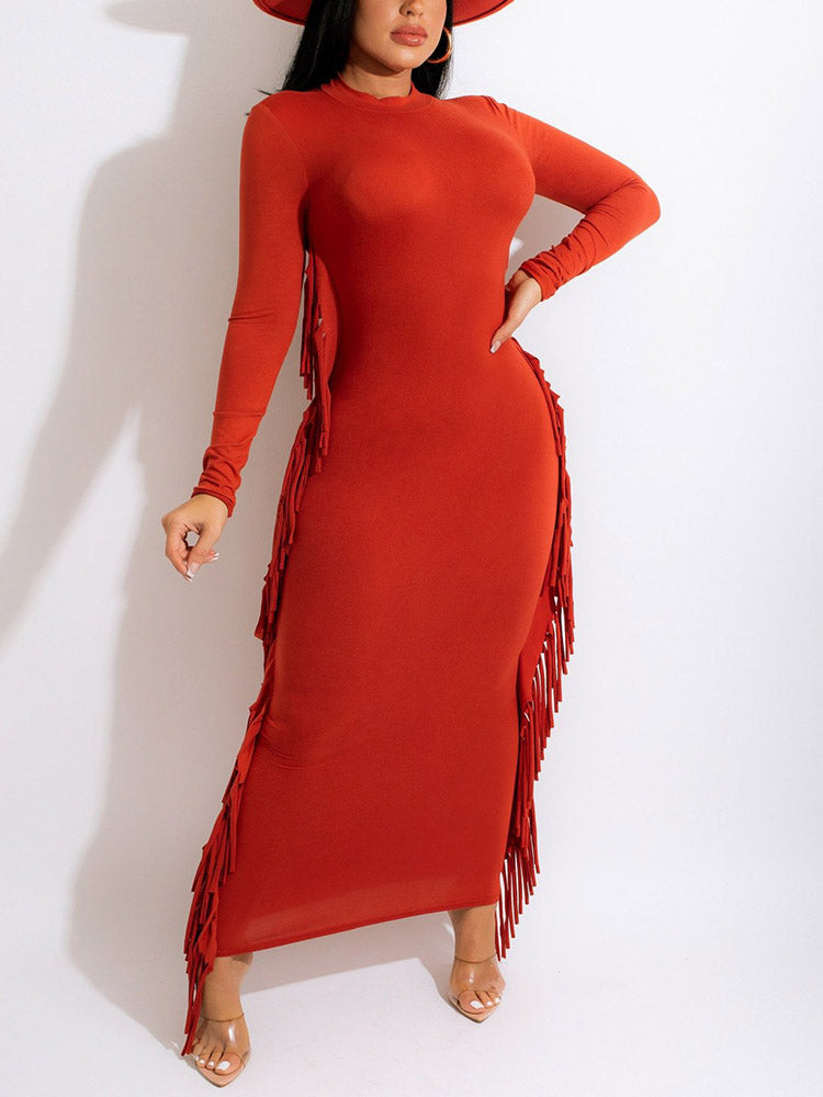Woman wearing a rust-colored long-sleeved maxi dress with fringe detailing.