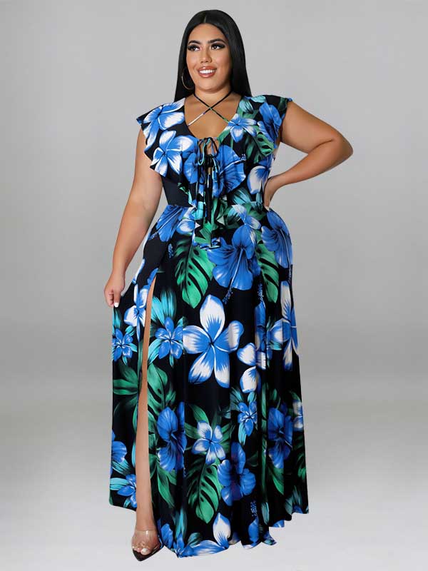 Woman wearing a black maxi dress with a blue and green floral print, featuring a V-neck with lace-up detail and a high slit.