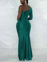 Back view of a woman in a green, one-shoulder evening dress with a fitted silhouette and a flared hem.