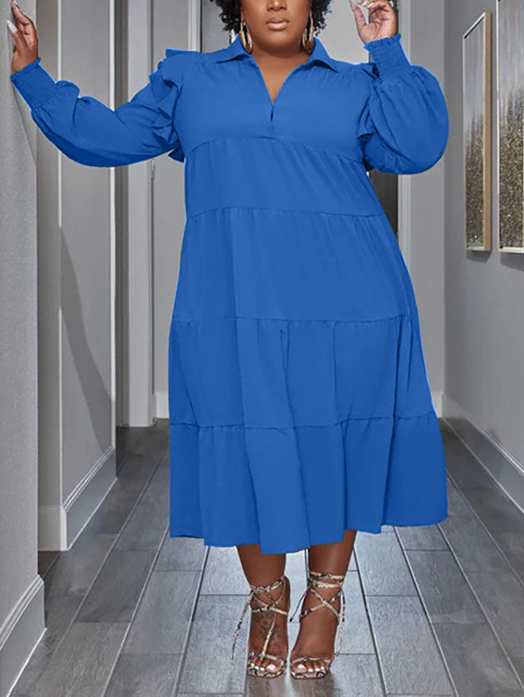 Plus-size model wearing a royal blue tiered midi dress with voluminous sleeves and ruffled shoulders.