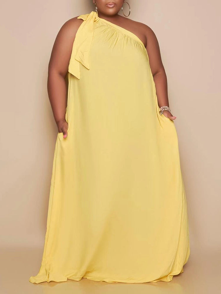 plus-size woman wearing a yellow one-shoulder maxi dress with pockets