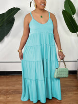 Woman wearing a light blue tiered maxi dress with spaghetti straps and a v-neckline, holding a mint green handbag.