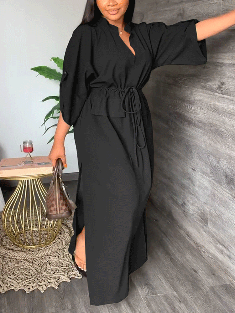 Woman in a black maxi dress with batwing sleeves and a cinched waist.