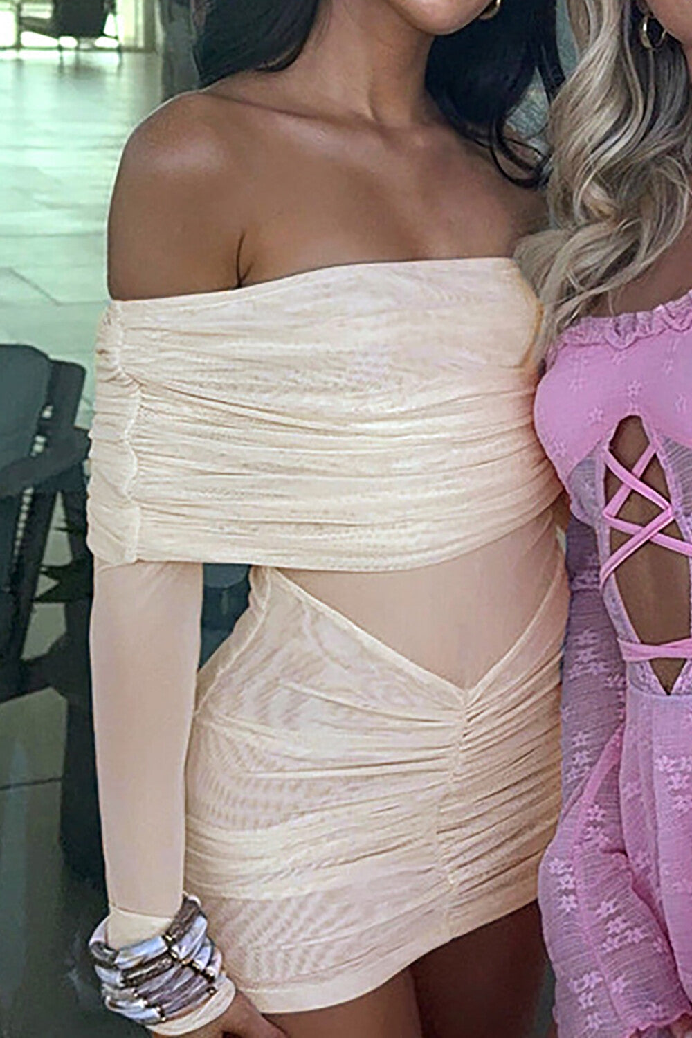 woman in a cream off-the-shoulder ruched mini dress with a friend