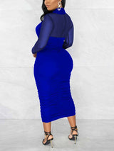 Back view of a woman in a royal blue ruched sheath dress with a criss-cross neckline and sheer long sleeves.