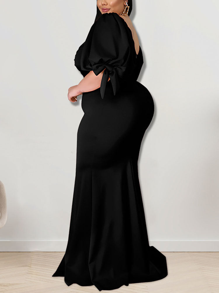 Side view of a woman in a black mermaid gown with puffed sleeves