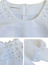 Close-up of pearl embellishments and sleeve detail on white dress