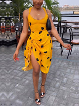 Woman wearing a yellow sleeveless dress with black hearts and a high slit.