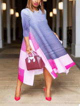 Full body shot of a woman in a blue and pink striped pleated A-line dress with an asymmetrical hem.