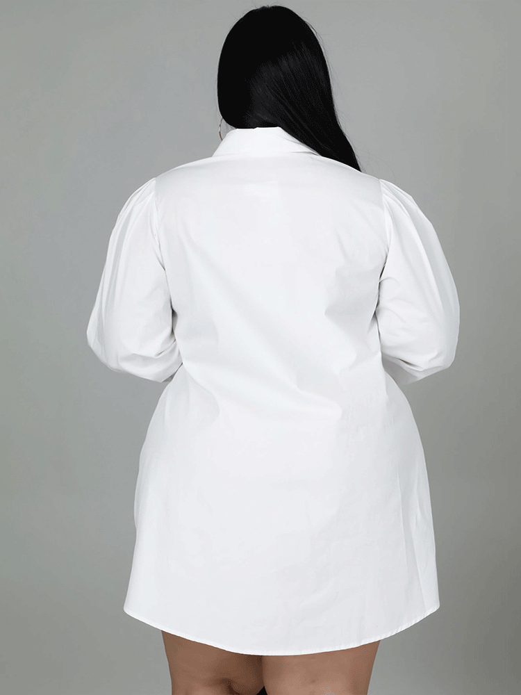 Back view of a plus-size woman wearing a white shirt dress, showing the puff sleeves and hemline.