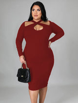 Woman wearing a burgundy long-sleeved ribbed knit bodycon dress with a cutout neckline and a black handbag.