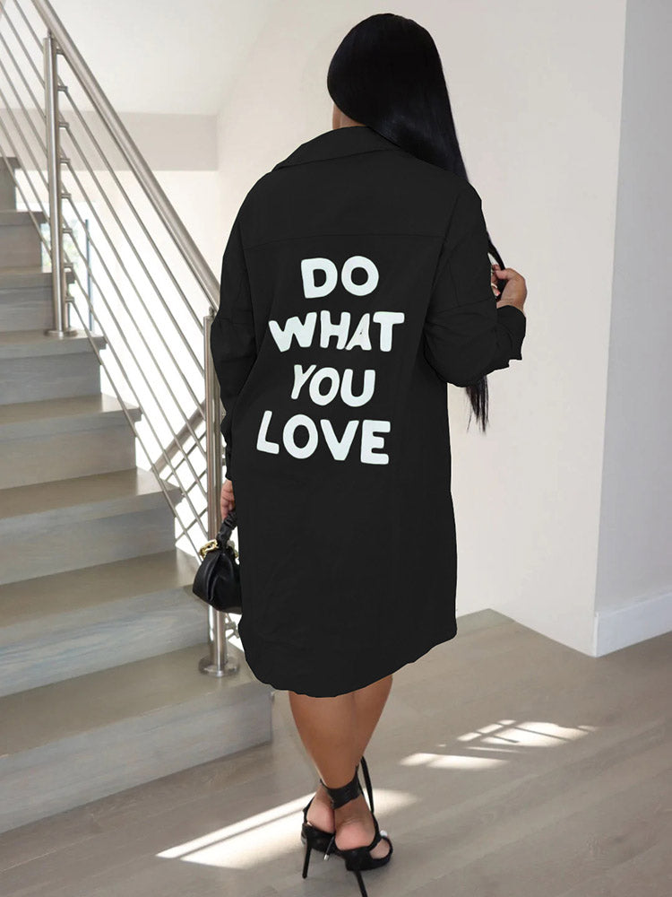 Back view of a woman wearing a black long-sleeve button-down shirt dress with 'DO WHAT YOU LOVE' graphic print.