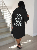 Back view of a woman wearing a black long-sleeve button-down shirt dress with 'DO WHAT YOU LOVE' graphic print.