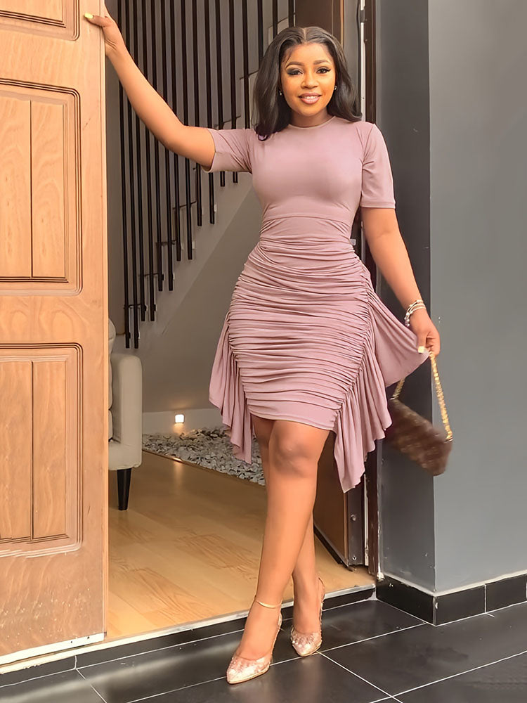 Woman in a mauve ruched dress holding a furry handbag.