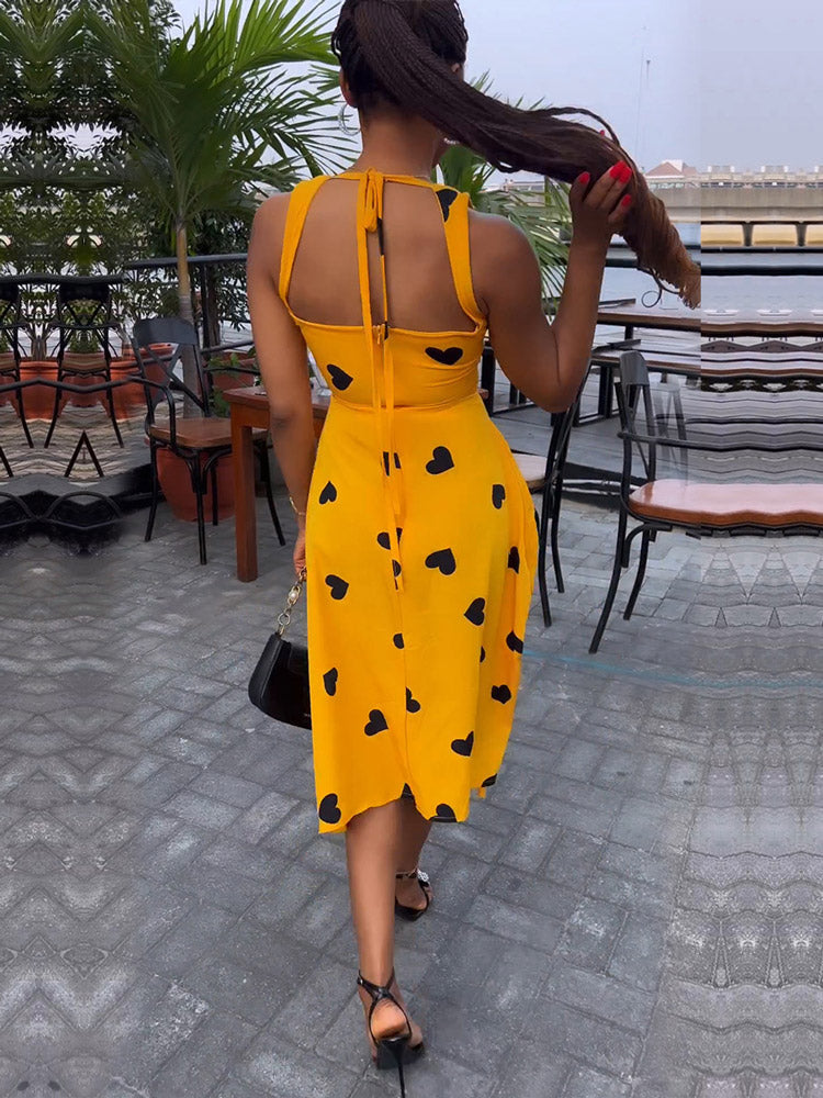 Rear view of a woman in a yellow heart-print dress with a halter neckline.