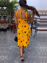 Rear view of a woman in a yellow heart-print dress with a halter neckline.